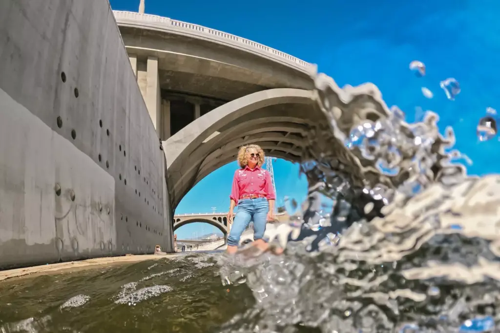 Artist Lauren Bon dipping into the Los Angeles River, whose water will be used to irrigate Los Angeles Historic Park as part of an ambitious environmental art project. (Allen J. Schaben / Los Angeles Times)